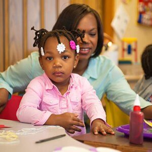 young girl in preschool with her teacher