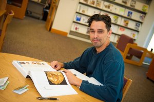 man in library reading an art history textbook